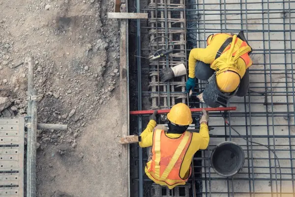 Construction workers collaborating on a busy construction site, wearing safety gear and operating machinery.